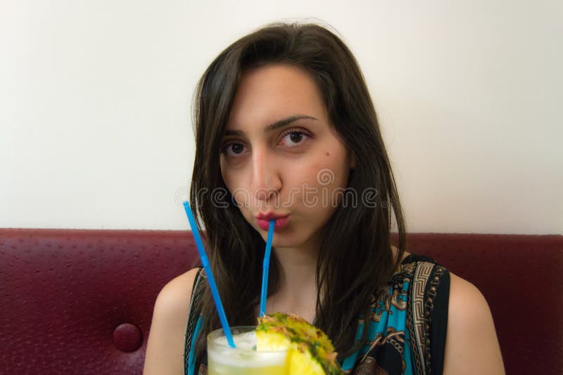 Schönes Mädchen, das ein Cocktail trinkt und direkt schaut lizenzfreie stockfotos Schönes Mädchen, das ein Cocktail trinkt und direkt schaut lizenzfreie stockfotos