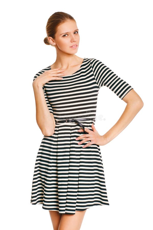 Schönes Mädchen, das in gestreiftem weißem Kleid mit der Hand auf Hüfte gegen weißen Hintergrund aufwirft lizenzfreie stockfotografie