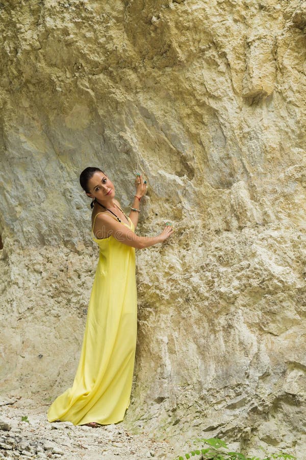 Schönes Mädchen in einem gelben Kleid nahe den Felsen lizenzfreie stockfotos Schönes Mädchen in einem gelben Kleid nahe den Felsen lizenzfreie stockfotos