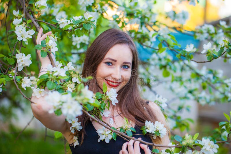 Schönes Mädchen in einem langen Rock unter einem blühenden Apfel stockfoto