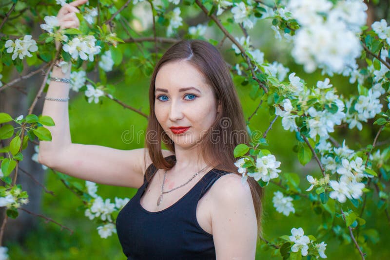 Schönes Mädchen in einem langen Rock unter einem blühenden Apfel lizenzfreie stockfotografie
