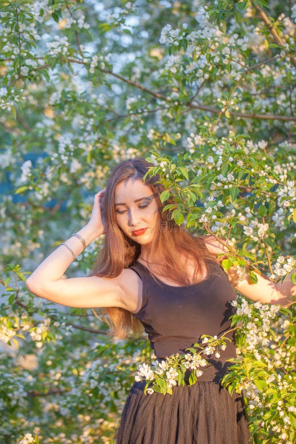 Schönes Mädchen in einem langen Rock unter einem blühenden Apfel lizenzfreie stockfotografie