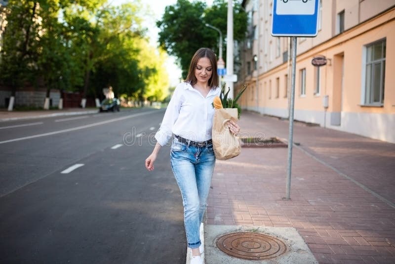 Schönes Mädchen mit Papiertüte mit Lebensmitteln. stockbild