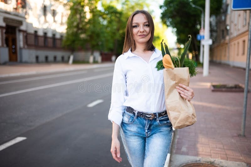 Schönes Mädchen mit Papiertüte mit Lebensmitteln. stockbild
