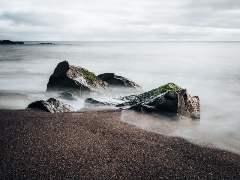Schönes ruhiges Meer mit Sandstrand und großen Steinen lizenzfreies stockbild