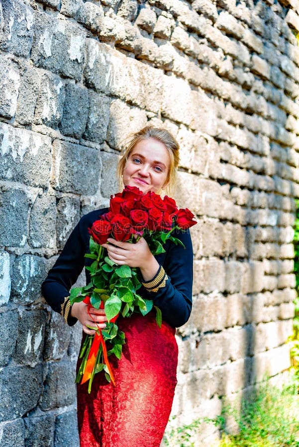 Schönes und sexy Mädchen mit einem Blumenstrauß von roten Rosen steht auf dem Hintergrund einer alten Backsteinmauer stockbilder Schönes und sexy Mädchen mit einem Blumenstrauß von roten Rosen steht auf dem Hintergrund einer alten Backsteinmauer stockbilder