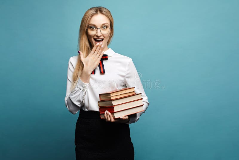 Schönes und überraschtes blondes vorbildliches Mädchen in der modernen Bluse, im stilvollen schwarzen Rock und in den Gläsern, mi stockfoto Schönes und überraschtes blondes vorbildliches Mädchen in der modernen Bluse, im stilvollen schwarzen Rock und in den Gläsern, mi stockfoto