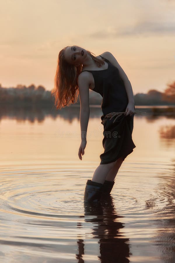 Schönheit ist im Wasser in einem Weiher bei Sonnenuntergang. sexy Frau im See stockfoto