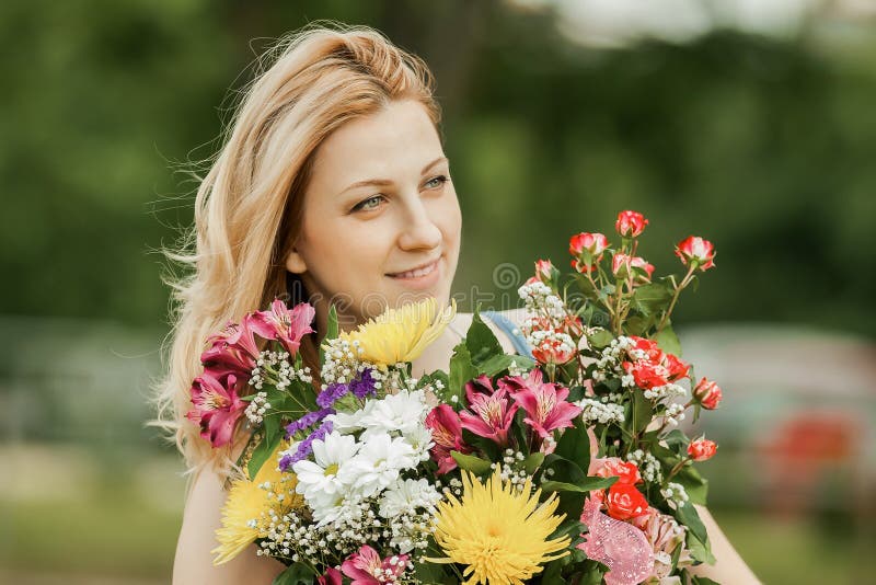 Schönheit mit einem Strauß von Blumen auf einem unscharfen Hintergrund des Parks lizenzfreie stockfotografie