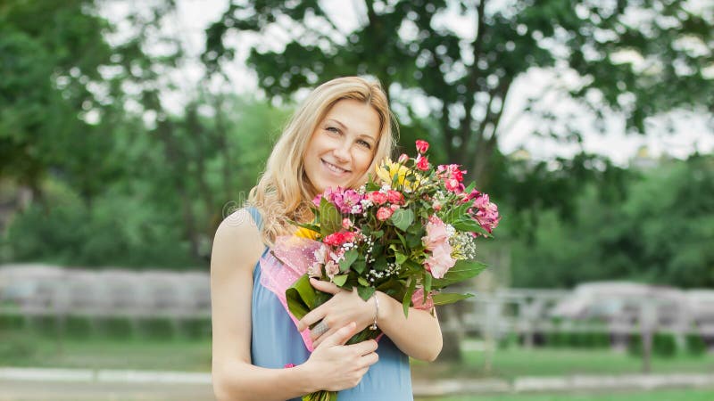 Schönheit mit einem Strauß von Blumen, die auf dem Gras im Stadt Park stehen lizenzfreie stockfotos