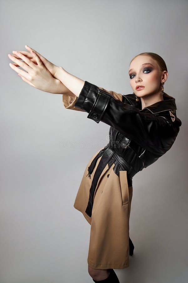 Schönheit Mode junge Frau in Trench Mantel professionelle Gesicht Make-up Mädchen. Frauenporträt auf weißem Hintergrund. Federklei. Frühlingskleidung bei Regenwetter.