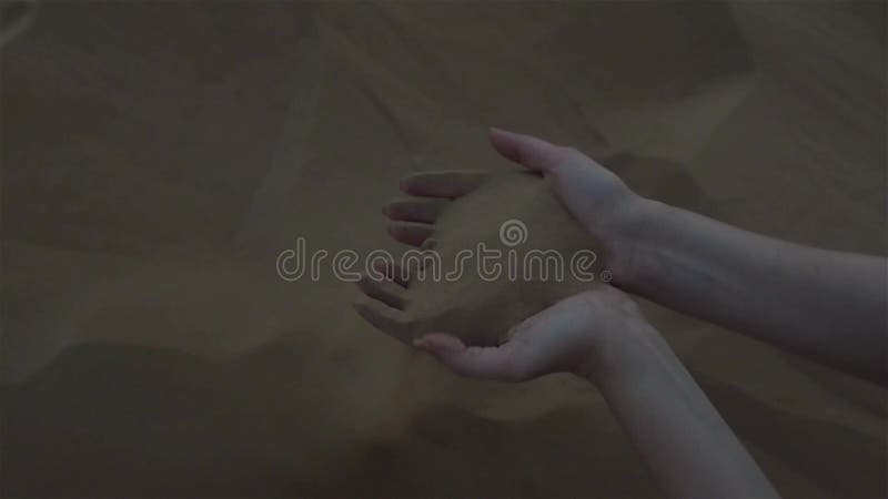 Schönheiten ` s Hände berühren den Sand, das Sandflattern im Wind