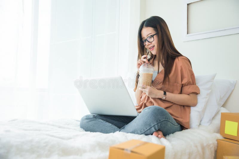 Schönheits-Asiatin, die Laptop verwendet und Kaffee auf Bett trinkt Gesch?fts- und Technologiekonzept Lieferung und on-line-Einka lizenzfreies stockbild Schönheits-Asiatin, die Laptop verwendet und Kaffee auf Bett trinkt Gesch?fts- und Technologiekonzept Lieferung und on-line-Einka lizenzfreies stockbild
