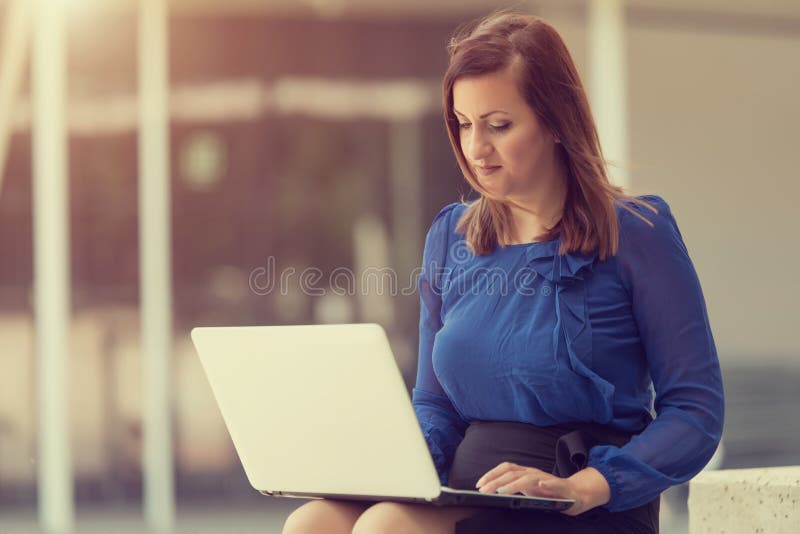 Schönheitsfrau, die einen Laptop sitzt und verwendet