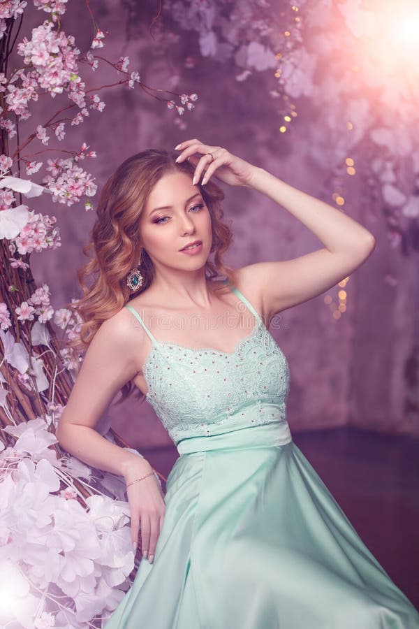 Schönheitsmodell in einem mintcolored Kleid auf einem geblühten Frühlingshintergrund. Schönheitsmädchen mit einem erstaunlichen Zu stockbilder