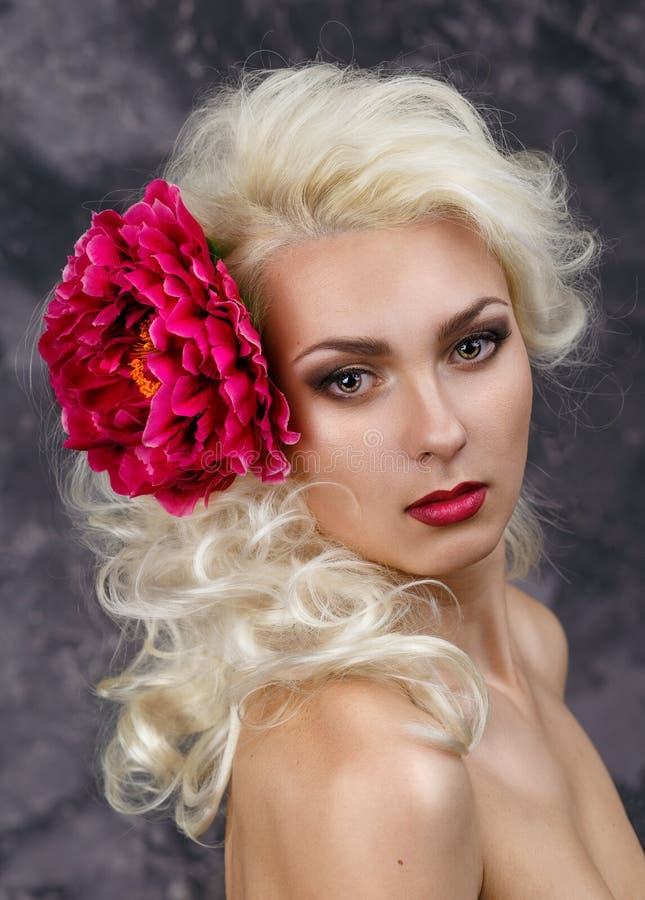 Beauty portrait of a blonde with a big red flower in her hair. healthy skin. spa. Beauty portrait of a blonde with a big red flower in her hair. healthy skin. spa.