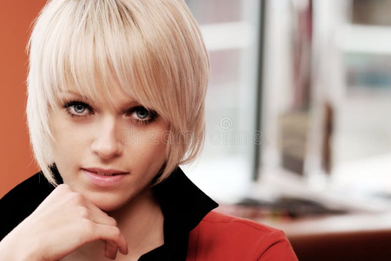 Beauty portrait of a beautiful young blond woman with short hair and blue eyes holding the chin with the hand and looking at the camera. Beauty portrait of a beautiful young blond woman with short hair and blue eyes holding the chin with the hand and looking at the camera