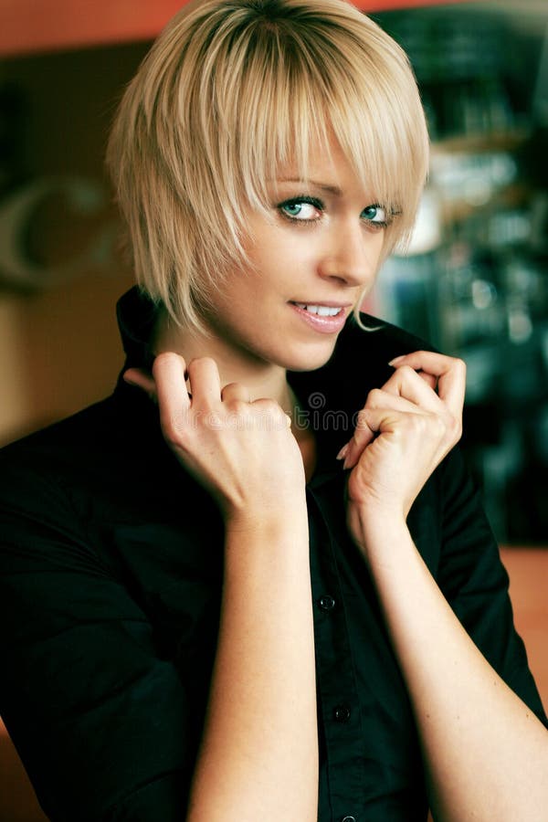 Beauty portrait of a beautiful young blond woman with short hair holding up the collar of the shirt. Beauty portrait of a beautiful young blond woman with short hair holding up the collar of the shirt