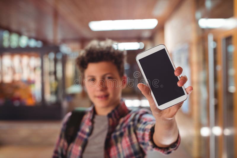 Schüler, der mit der Schultasche in der Schule zeigt Handy im Korridor steht stockfoto Schüler, der mit der Schultasche in der Schule zeigt Handy im Korridor steht stockfoto
