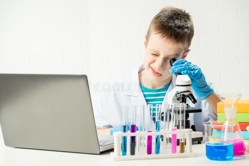 Schüler mit Laptop im Labor führt chemische Experimente mit Substanzen im Reagenzglas-Portrait durch lizenzfreie stockbilder