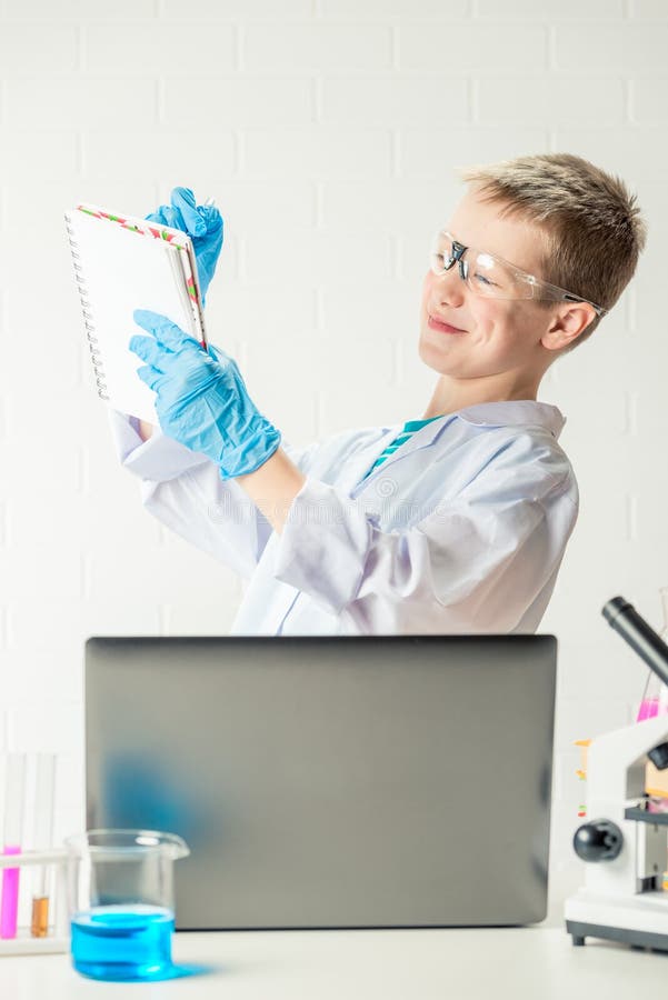 Schüler mit Laptop im Labor führt chemische Experimente mit Substanzen im Reagenzglas-Portrait durch stockfoto