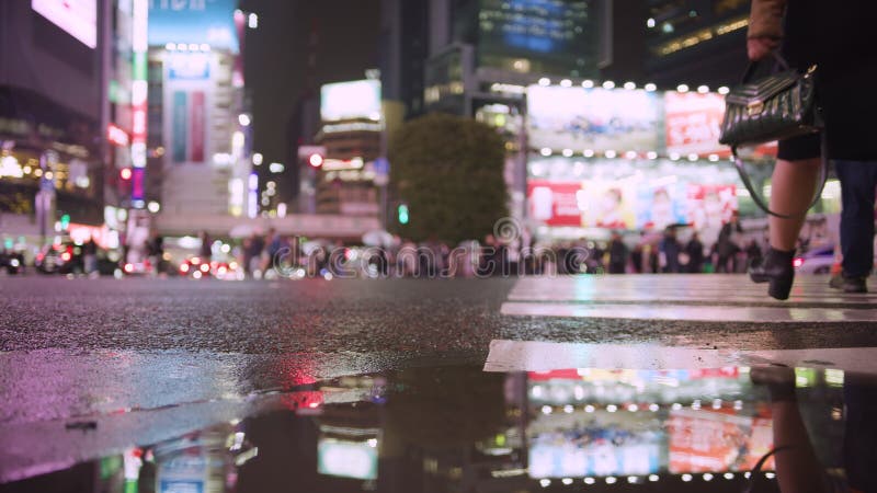 Schüsse von Menschen in Shibuya Kreuzung Platz in einer regnerischen Nacht. zeigt Shopper und Nachtleben in der Neonstadt