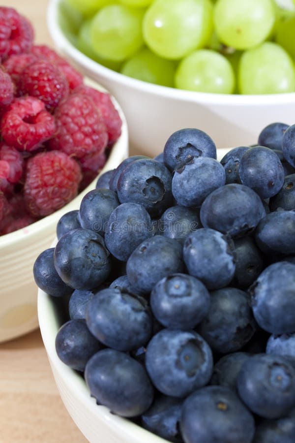 Three bowls of healthy breakfast berries, raspberries, blueberries and grapes. Three bowls of healthy breakfast berries, raspberries, blueberries and grapes