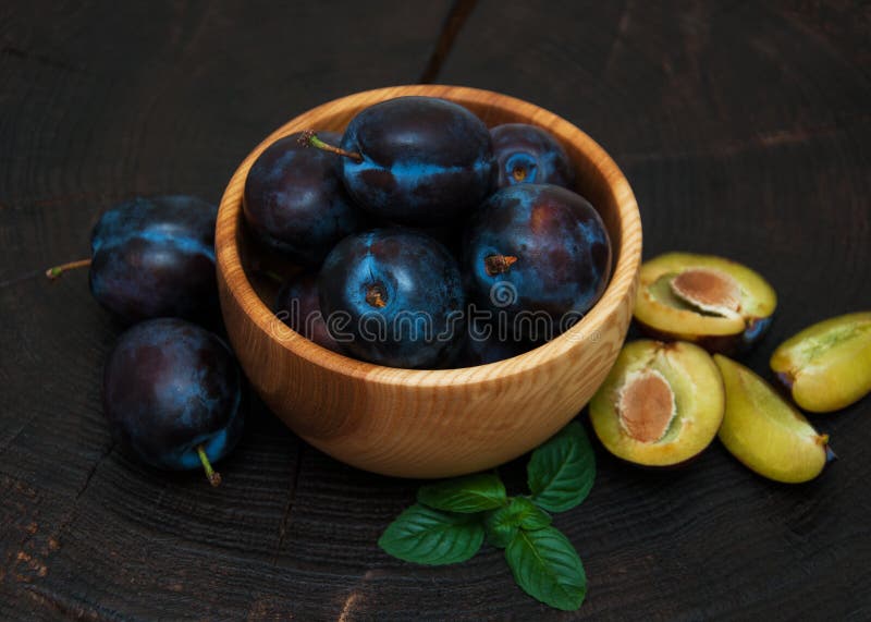 Schüssel mit Pflaumen mit grünen Blättern stockfotografie Schüssel mit Pflaumen mit grünen Blättern stockfotografie