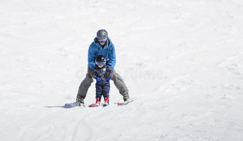 Sci del ragazzo del bambino in discesa con l'aiuto di suo padre immagini stock libere da diritti Sci del ragazzo del bambino in discesa con l'aiuto di suo padre immagini stock libere da diritti