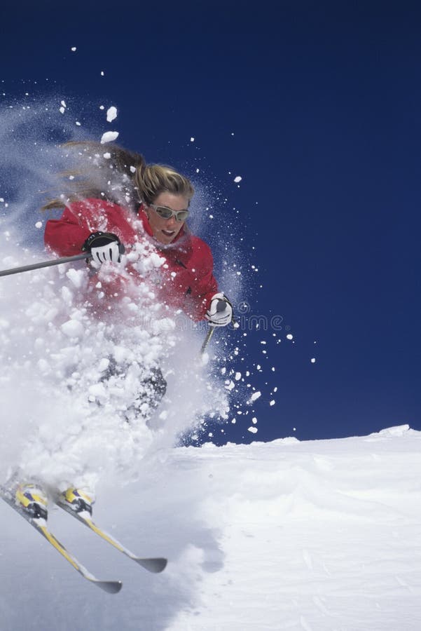 Sciatore attraverso neve polverosa sul pendio