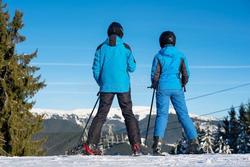 Sciatori della donna e dell'uomo sul paesaggio godente superiore della montagna immagine stock Sciatori della donna e dell'uomo sul paesaggio godente superiore della montagna immagine stock
