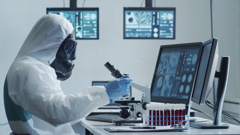 Scientifique en costumes de protection et masques travaillant en laboratoire de recherche à l'aide d'équipement de laboratoire : m
