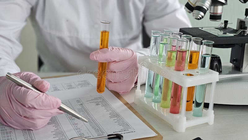 Scientist conducts experiment with test tubes and microscope in laboratory royalty free stock photos