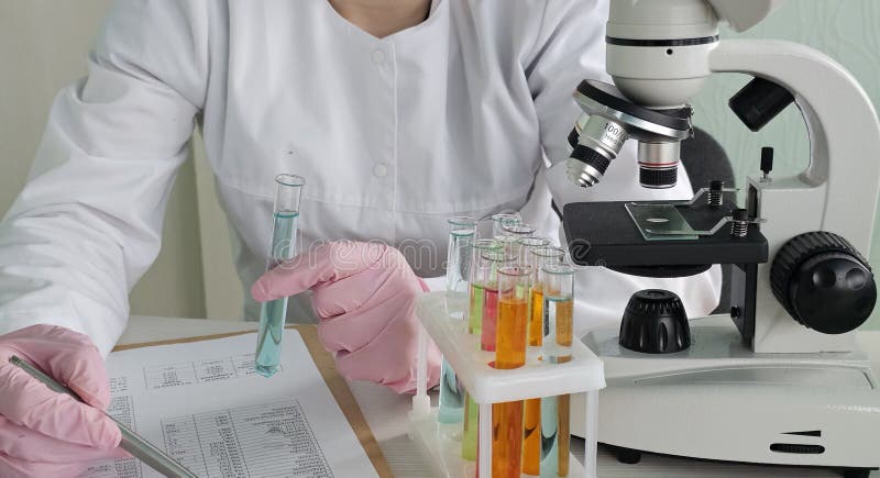 Scientist conducts experiments with test tubes and microscope in a laboratory stock image