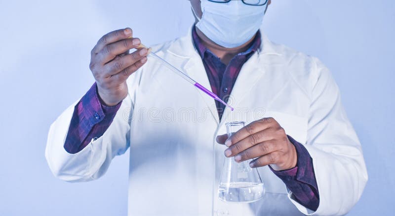 Scientist pouring color liquid into a Conical flask with a dropper in Chemistry Laboratory stock photo