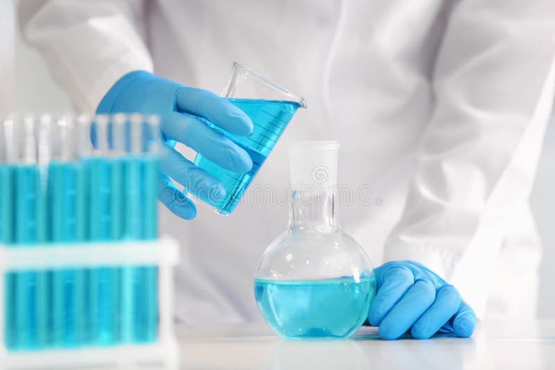 Scientist pouring color liquid into flask in laboratory royalty free stock photos