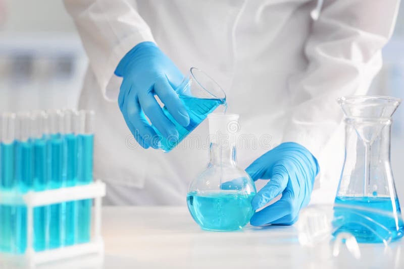 Scientist pouring color liquid into flask in laboratory royalty free stock image
