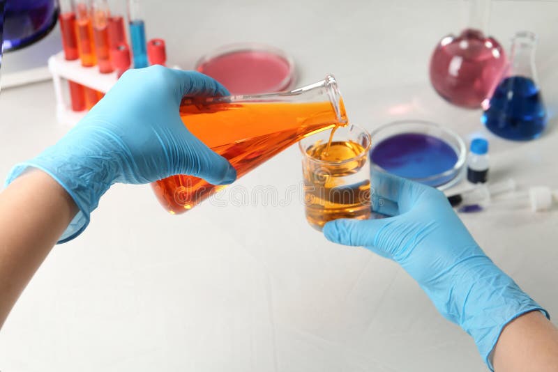 Scientist Pouring Reagent into Beaker at Table in Chemistry Laboratory