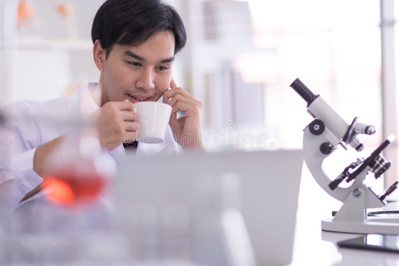 Scientists Wearing White Coats Sit in the Lab and Relax with a Coffee