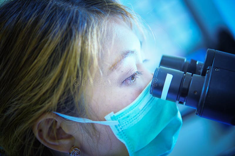 Scienziato che guarda tramite il microscopio nell'ospedale del laboratorio immagine stock Scienziato che guarda tramite il microscopio nell'ospedale del laboratorio immagine stock