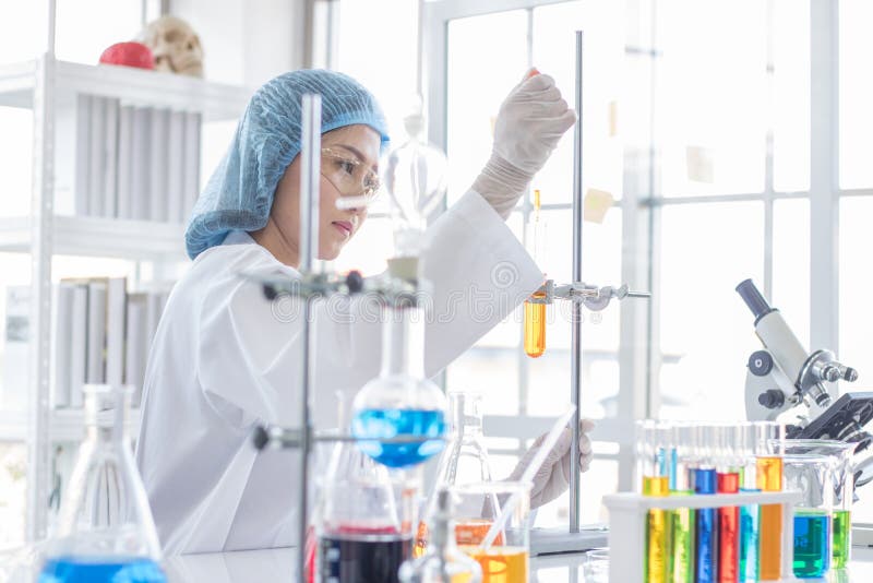 Scienziato femminile asiatico durante i prodotti chimici di studio fotografia stock libera da diritti Scienziato femminile asiatico durante i prodotti chimici di studio fotografia stock libera da diritti
