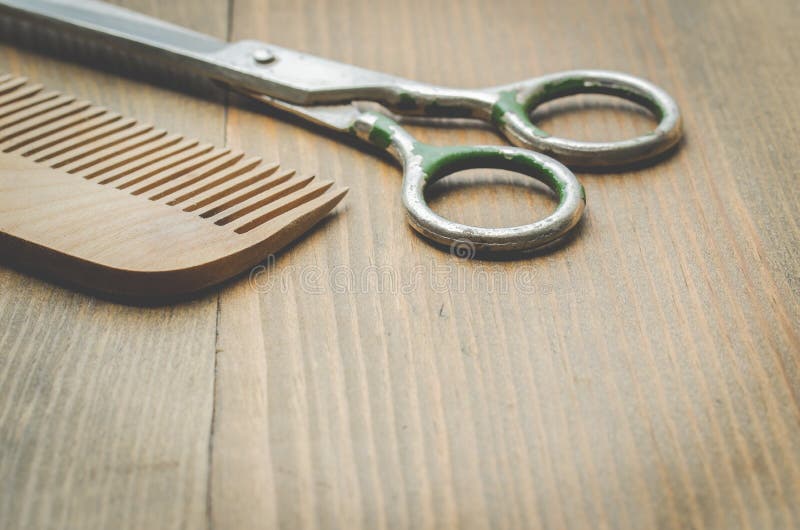 Scissors and comb on old wooden background, selective focus. Barbershop concept