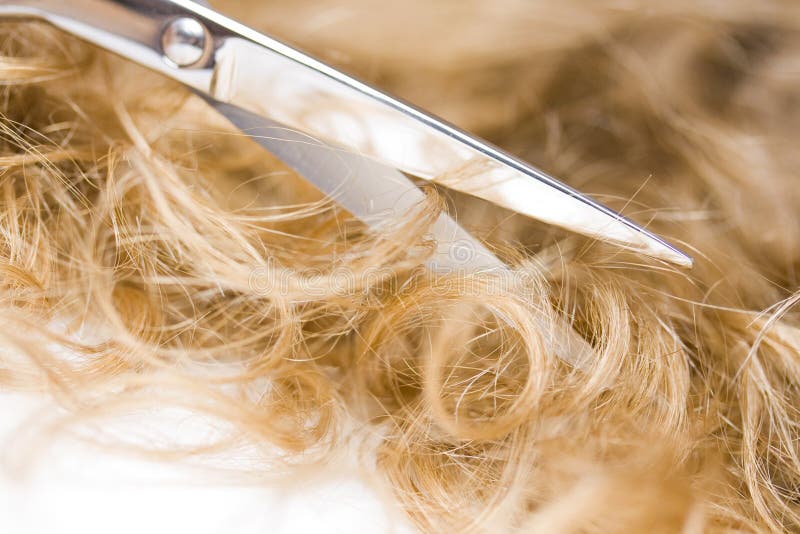 Scissors cutting blond hair