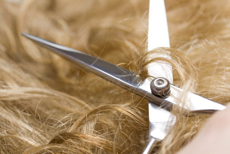 Scissors cutting blond hair