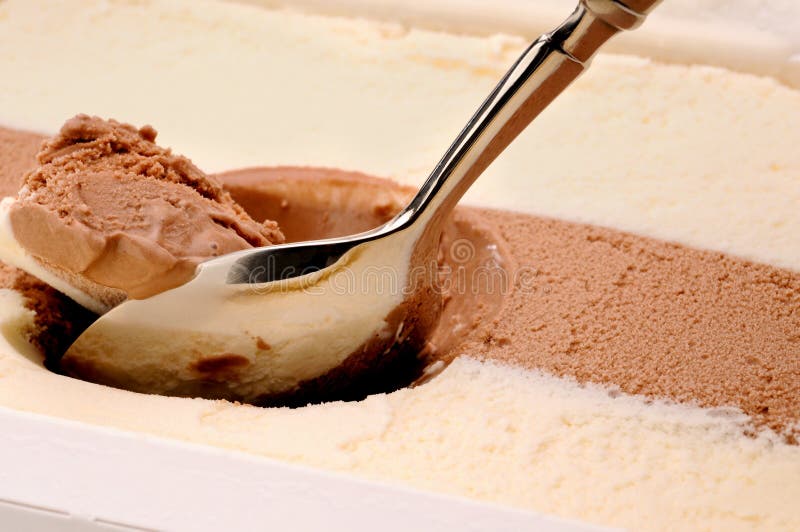 A silver spoon scooping out chocolate and vanilla ice cream. A silver spoon scooping out chocolate and vanilla ice cream