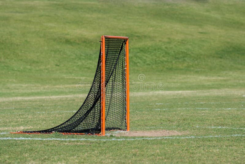 Single orange lacrosse goal with black netting, background green grass. Single orange lacrosse goal with black netting, background green grass