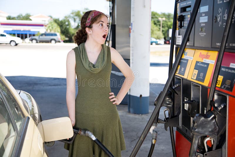 Young woman filling up her gas tank is shocked by the high fuel prices. Young woman filling up her gas tank is shocked by the high fuel prices.