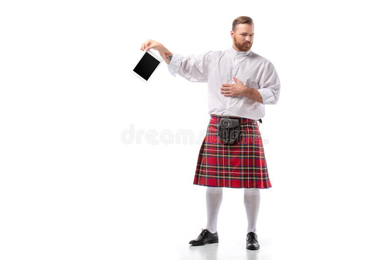 Displeased Scottish redhead man in red. Scottish redhead man in red kilt with digital tablet on white background royalty free stock image Displeased Scottish redhead man in red. Scottish redhead man in red kilt with digital tablet on white background royalty free stock image