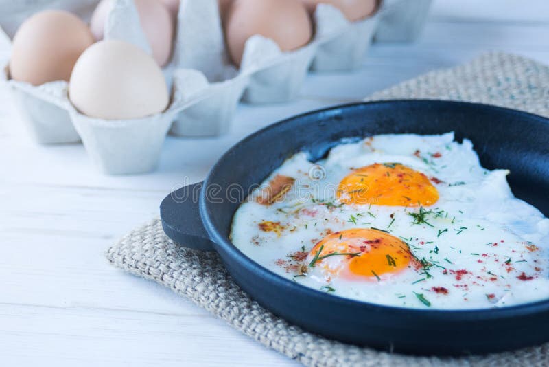 Scrambled Eggs in a Black Cast Iron Pan and Eggs in a Tray. Light