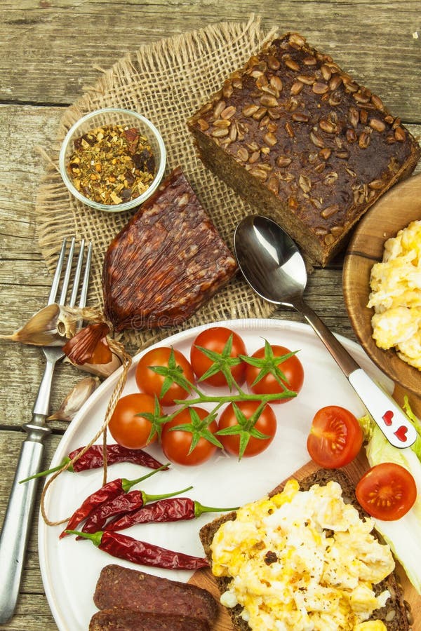 Scrambled Eggs with Bread and Salami. Egg Breakfast on a Wooden Table